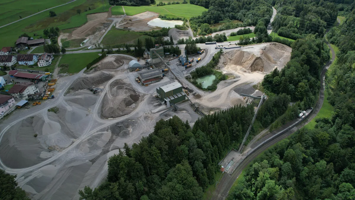 Luftaufnahme einer Abbaugrube in einer grünen Landschaft.